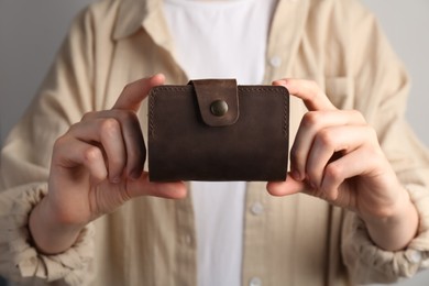 Photo of Woman holding leather business card holder on grey background, closeup