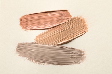 Image of Different shades of liquid foundation on beige background, top view