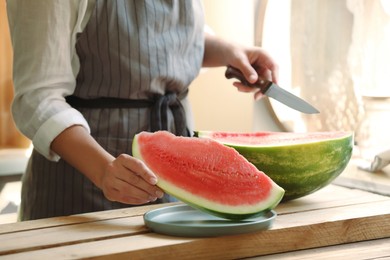 Photo of Woman with sliced fresh juicy watermelon at wooden table, closeup