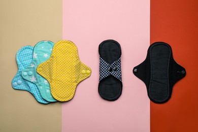 Many reusable cloth menstrual pads on color background, flat lay
