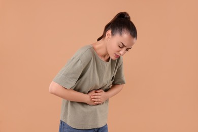 Photo of Woman suffering from abdominal pain on beige background. Unhealthy stomach