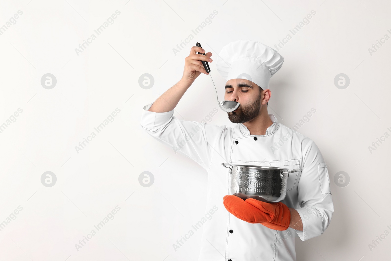 Photo of Professional chef tasting something on white background