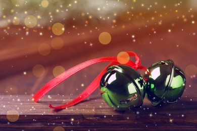 Green sleigh bells with red ribbon on wooden table, closeup