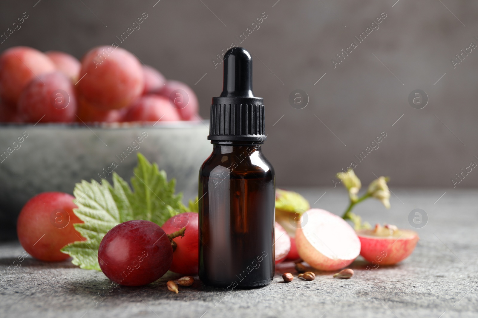 Photo of Bottle of natural grape seed oil on grey table. Organic cosmetic