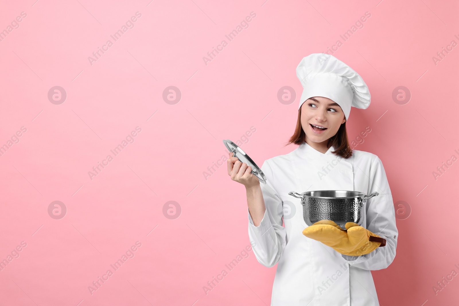 Photo of Professional chef with cooking pot on pink background. Space for text