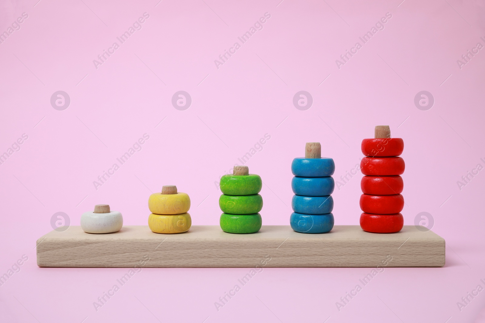 Photo of Stacking and counting game wooden pieces on pink background. Educational toy for motor skills development