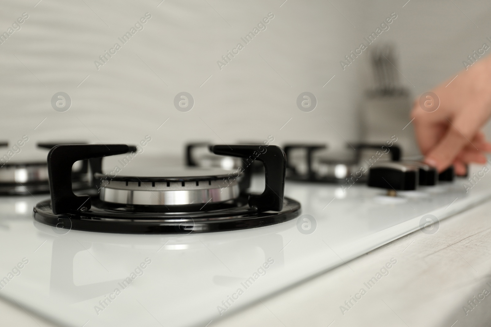 Photo of Woman regulating cooking mode on gas stove panel, closeup