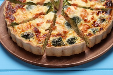 Delicious homemade quiche with salmon and broccoli on light blue wooden table, closeup