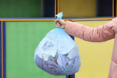 Photo of Woman with garbage bag at recycling point outdoors, closeup