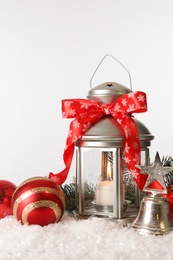 Beautiful composition with vintage Christmas lantern and festive decorations on snow against white background