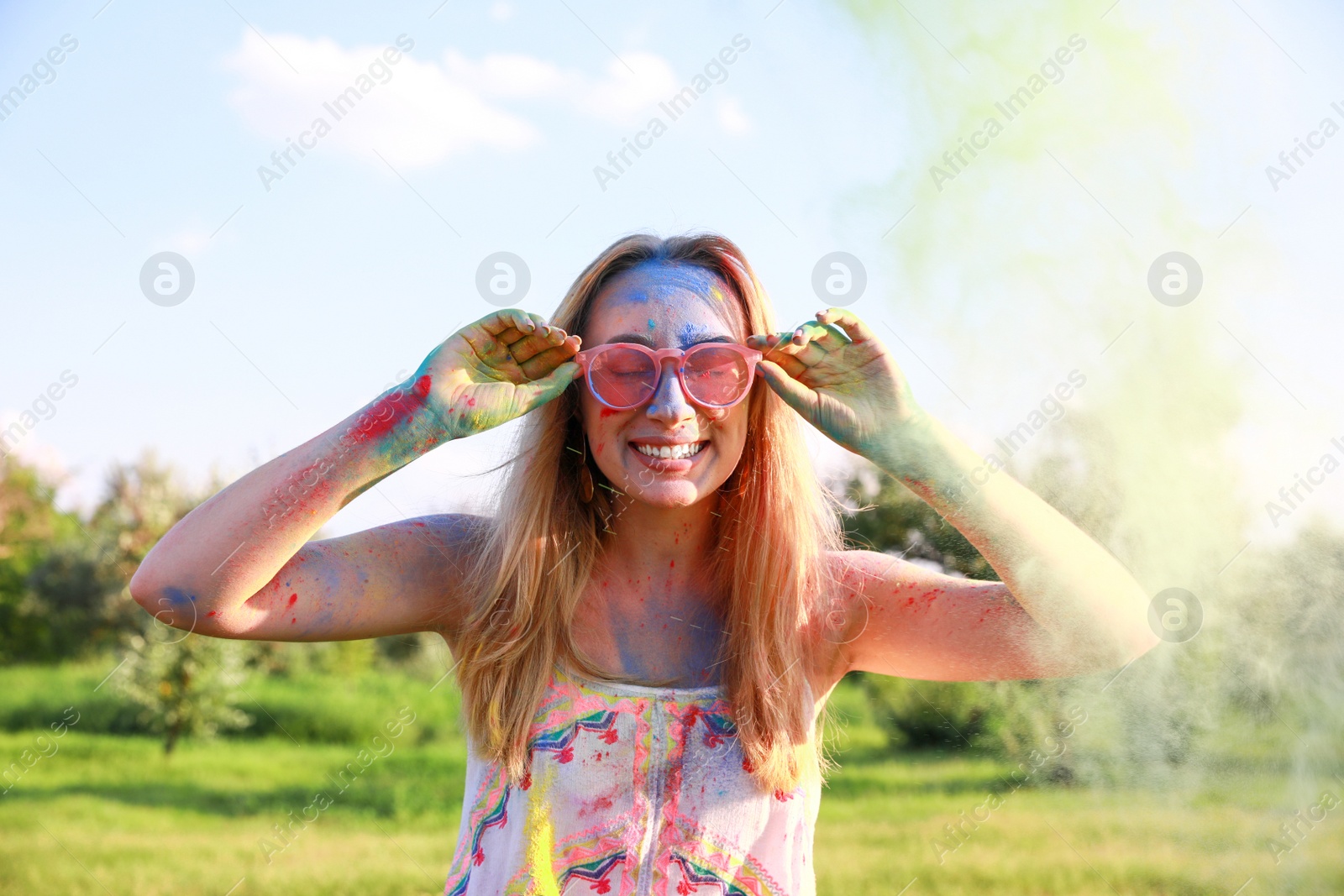 Photo of Happy woman covered with colorful powder dyes outdoors. Holi festival celebration