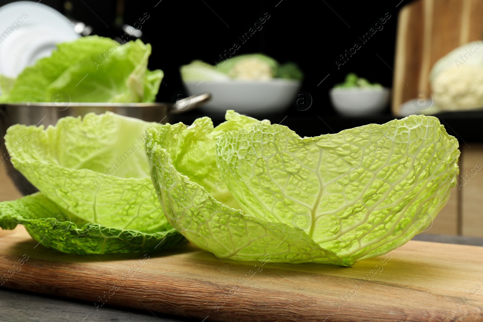 Photo of Fresh Savoy cabbage leaves on table in kitchen, closeup