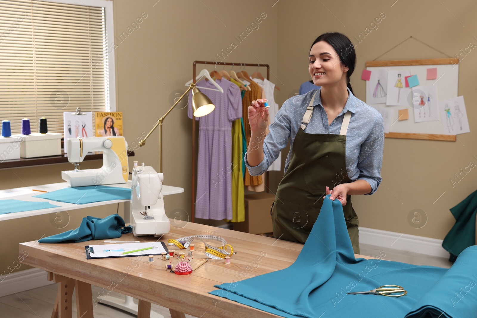 Photo of Dressmaker working with light blue fabric in atelier