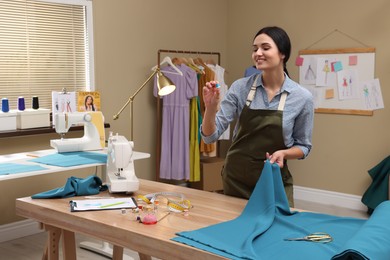 Photo of Dressmaker working with light blue fabric in atelier