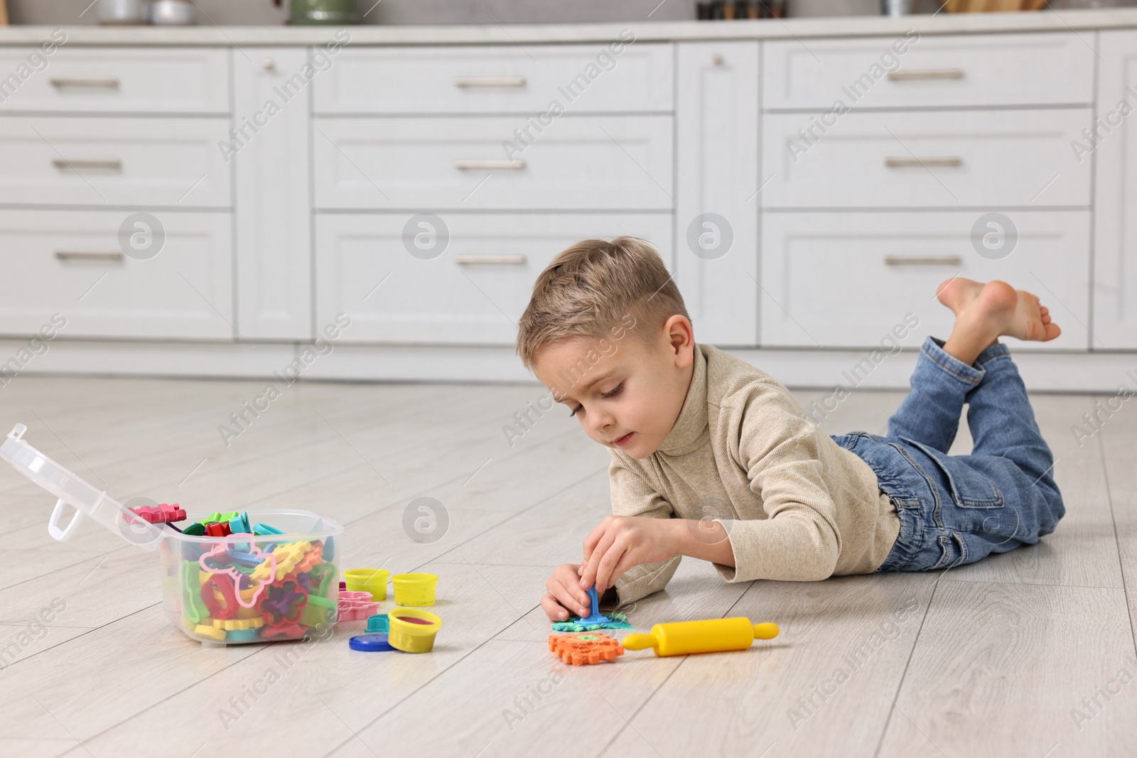 Photo of Cute little boy playing on warm floor in kitchen, space for text. Heating system