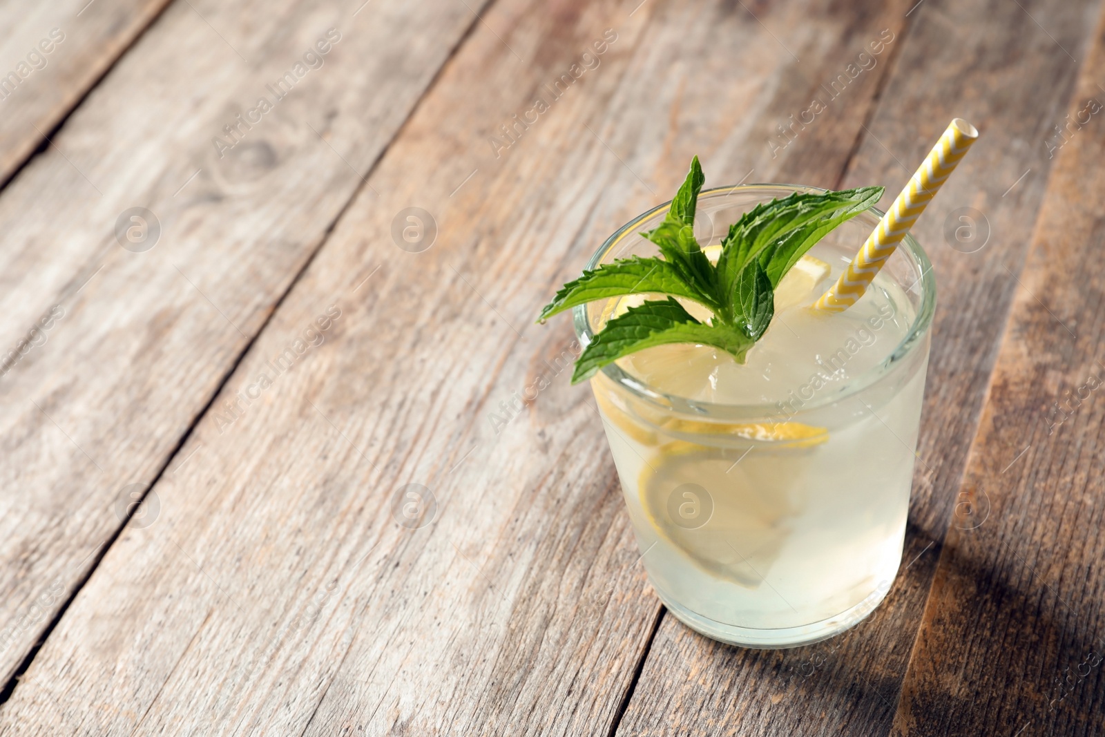 Photo of Natural lemonade with mint in glass on wooden table
