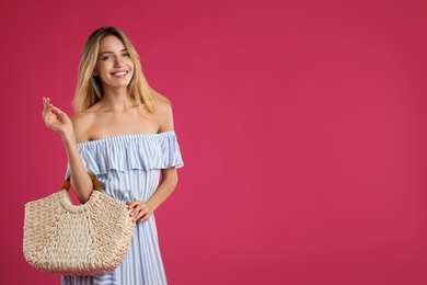 Photo of Beautiful young woman with stylish straw bag on pink background. Space for text