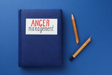 Photo of Notebook with words Anger Management and broken pencil on blue background, flat lay