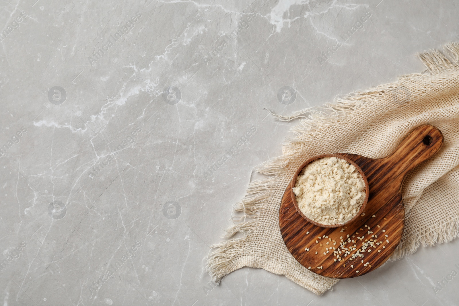 Photo of Bowl with sesame flour on light background