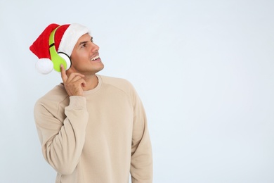 Photo of Happy man with headphones on white background, space for text. Christmas music