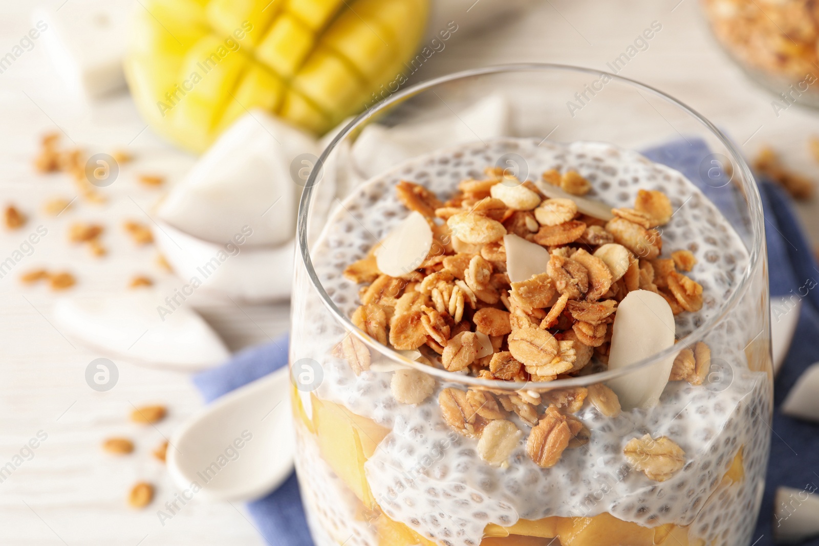 Photo of Delicious chia pudding with granola and mango in glass on table, closeup