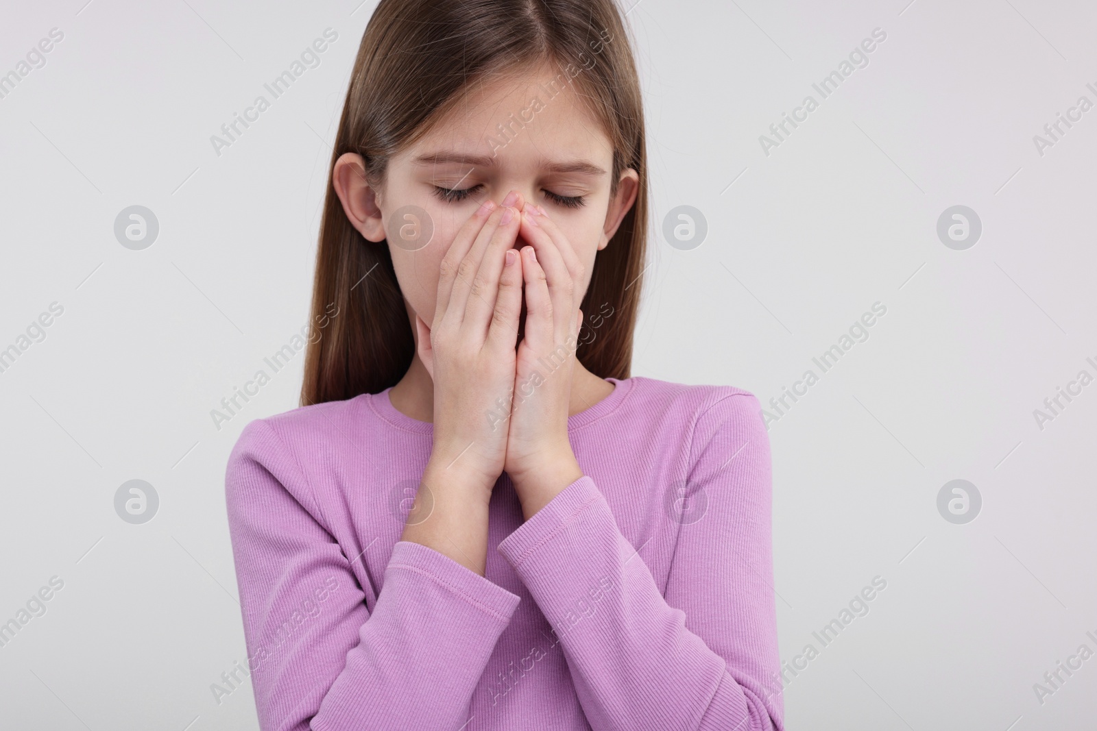 Photo of Sick girl coughing on light background. Cold symptoms