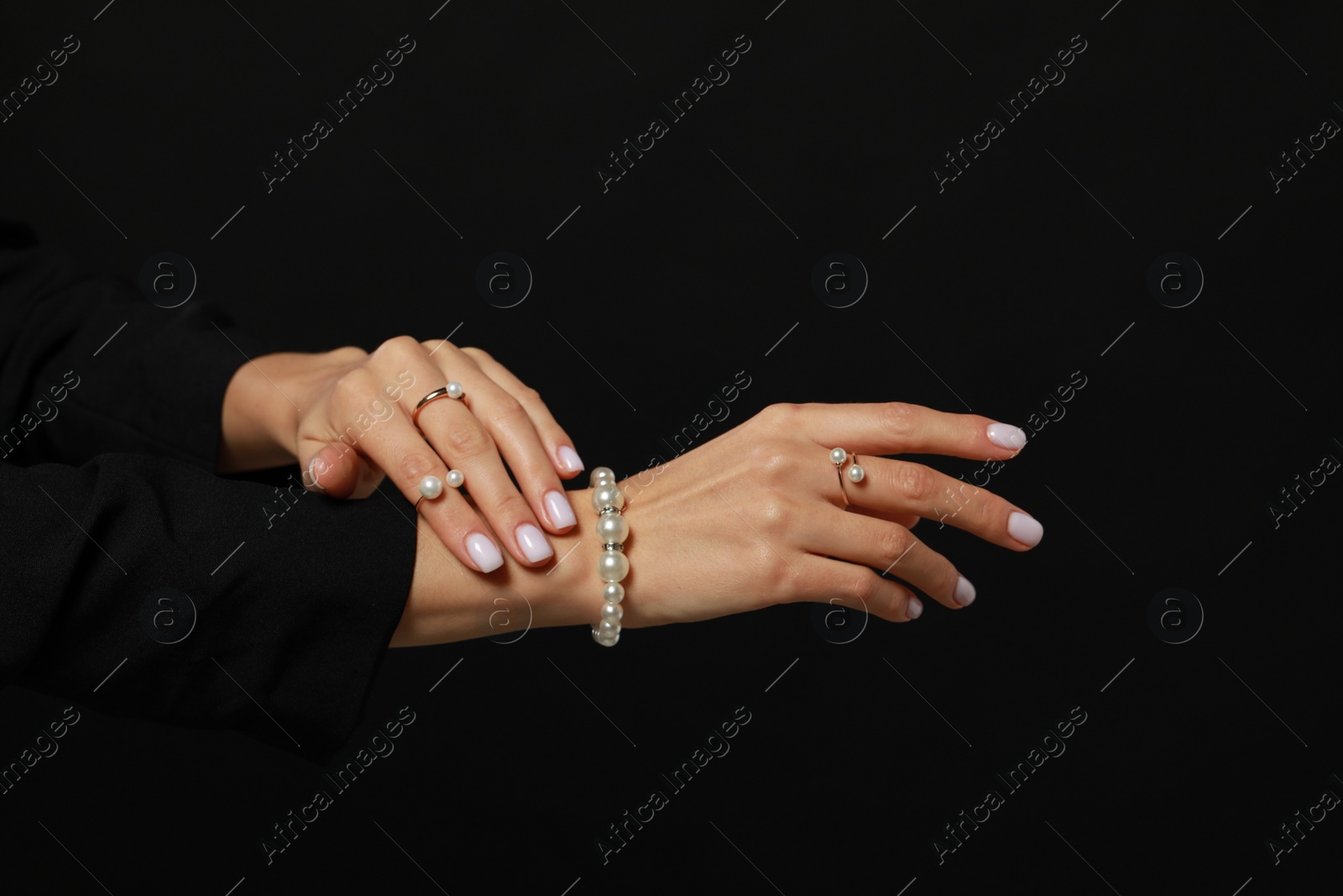 Photo of Young woman with elegant pearl jewelry on black background, closeup