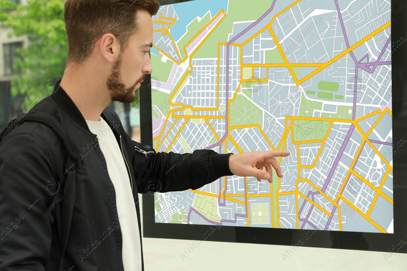 Image of Young man near public transport map at bus stop, closeup