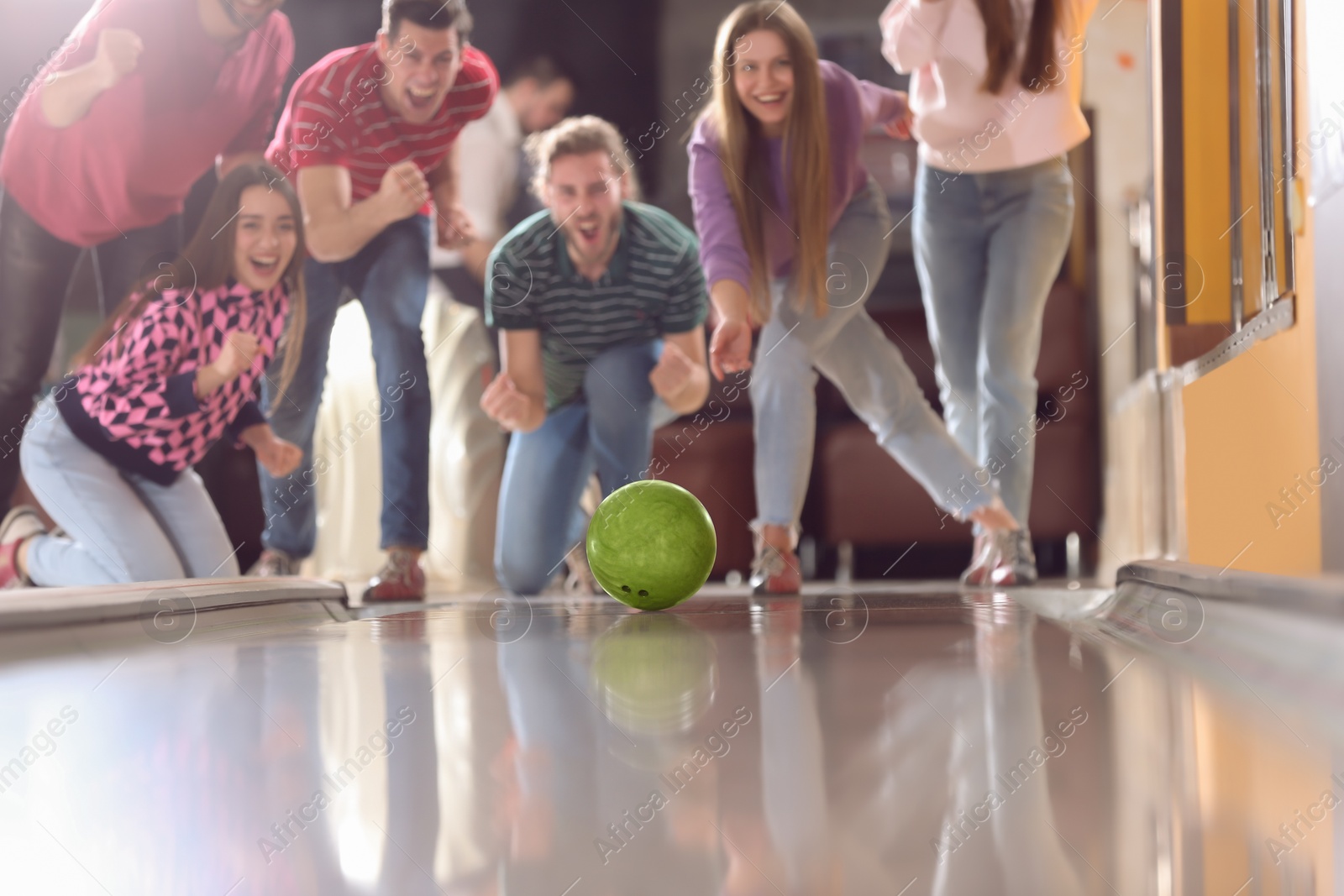 Photo of Young woman throwing ball and spending time with friends in bowling club