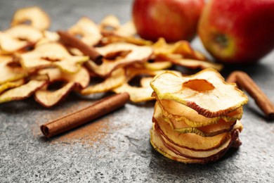 Photo of Delicious apple chips and cinnamon on grey table, closeup. Space for text