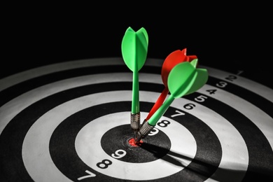 Photo of Arrows hitting target on dart board against black background