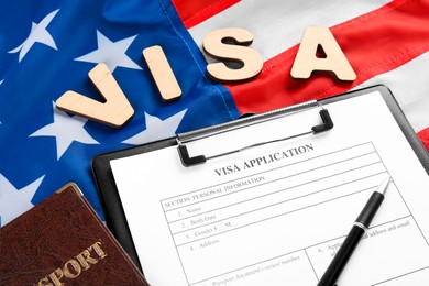 Photo of Word Visa, application form and passport on American flag. Immigration to USA