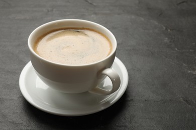 Photo of Cup of aromatic coffee on black table, closeup