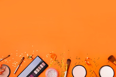 Different luxury makeup products on orange background, flat lay. Space for text