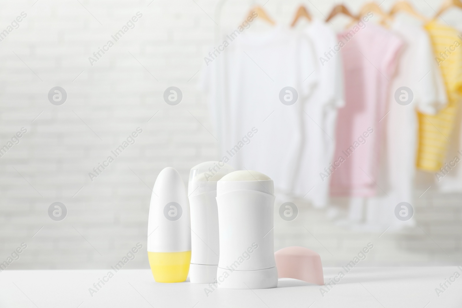 Photo of Different deodorants on white table in room. Space for text