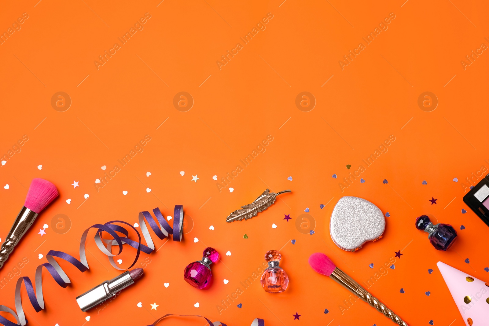 Photo of Different luxury makeup products on orange background, flat lay. Space for text