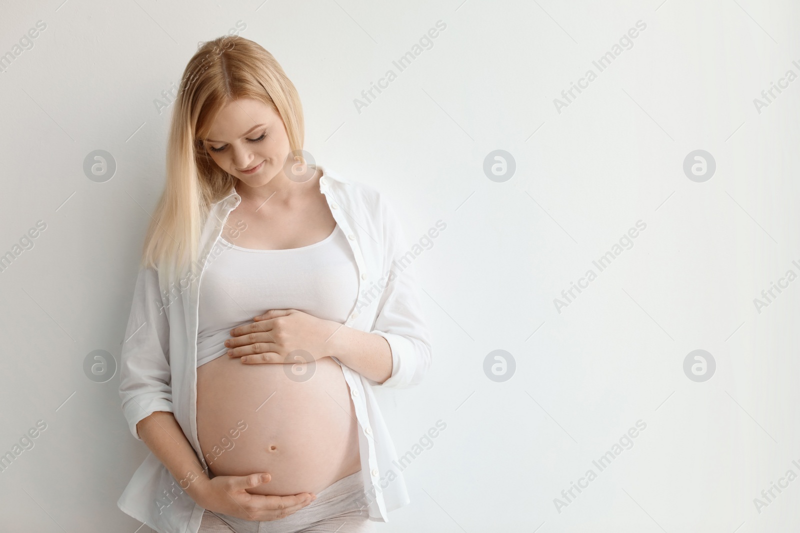 Photo of Portrait of beautiful pregnant woman on light background. Space for text