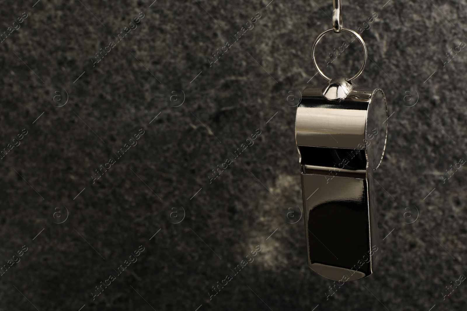 Photo of Referee equipment. Metal whistle on grey textured background, closeup and space for text