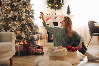 Beautiful woman decorating Christmas tree at home