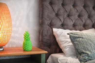 Photo of Pineapple shaped candle and lamp on bedside table in room