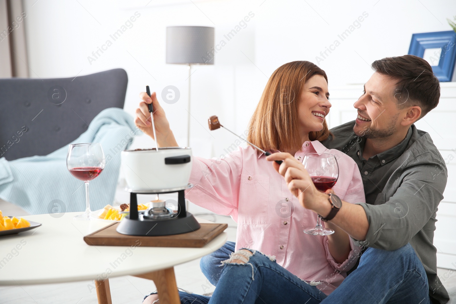 Photo of Happy couple enjoying fondue dinner at home