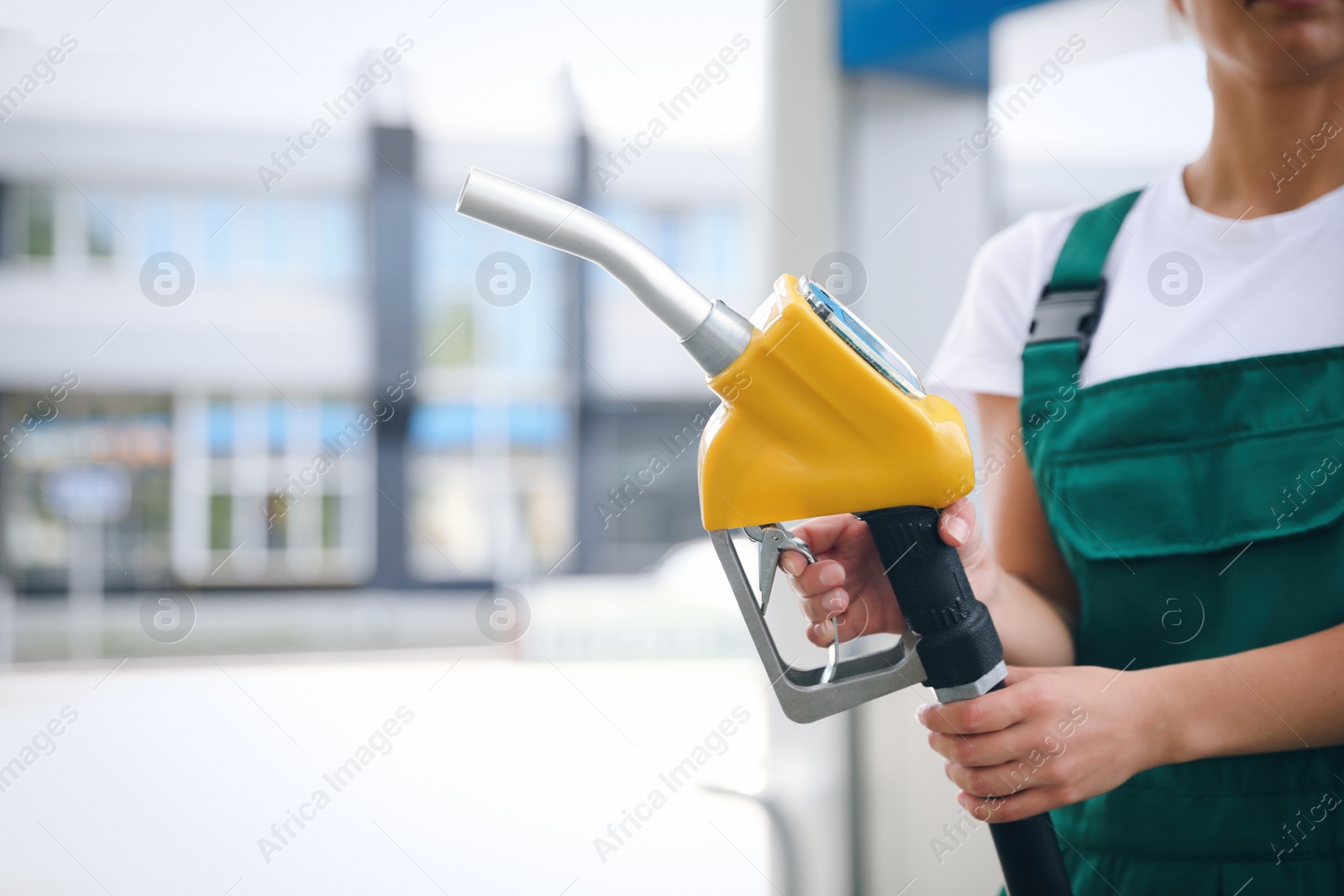 Photo of Young worker with fuel pump nozzle at modern gas station, closeup