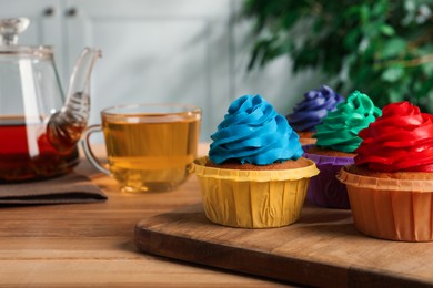 Photo of Delicious cupcakes with colorful cream on wooden table