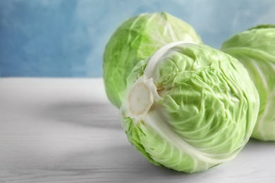 Photo of Whole cabbages on white table. Healthy food