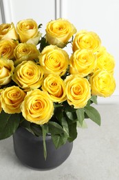 Beautiful bouquet of yellow roses in vase on light grey table