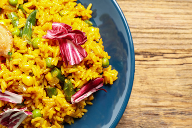 Photo of Delicious rice pilaf with chicken and vegetables on wooden table, closeup