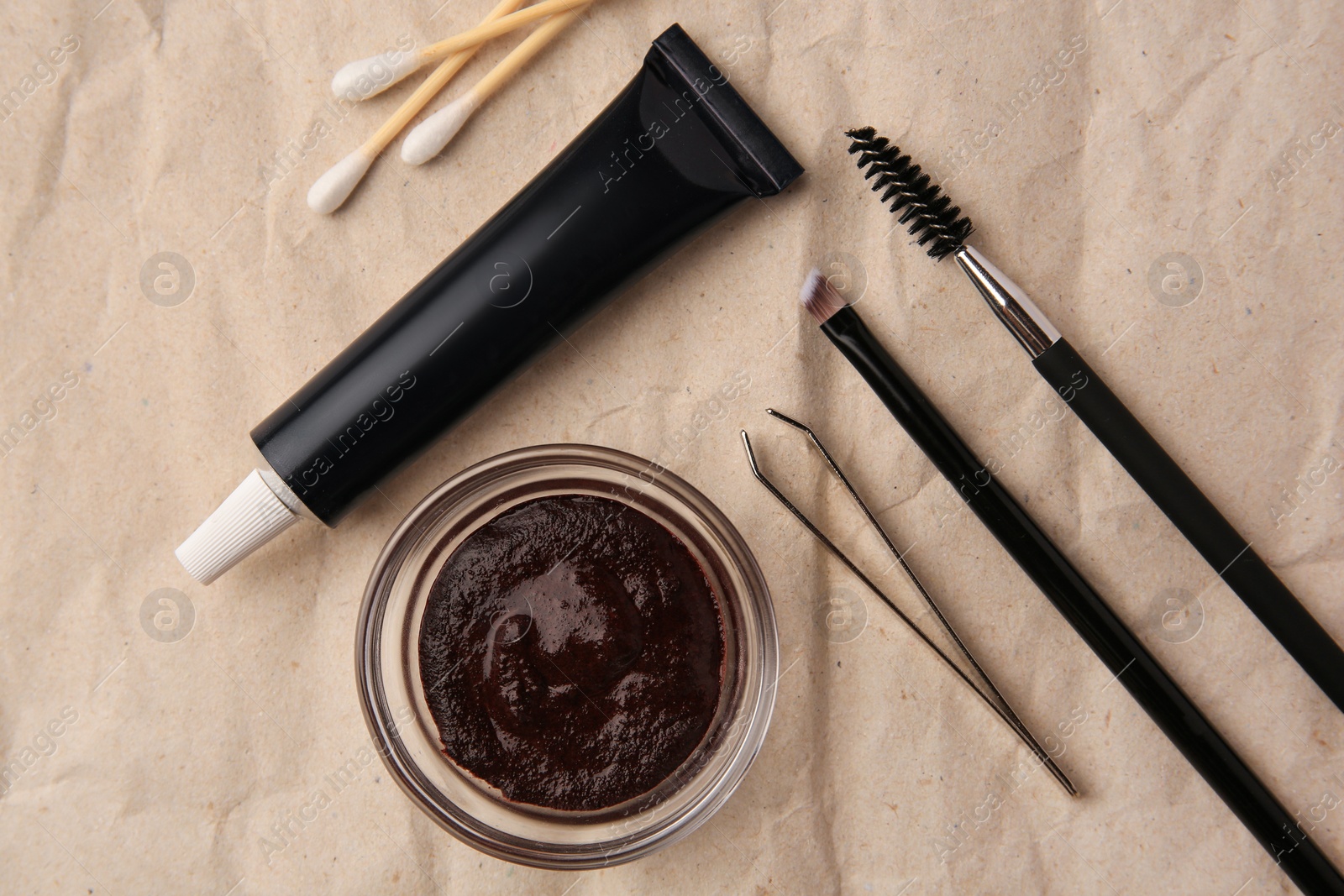 Photo of Flat lay composition with eyebrow henna and tools on crumpled paper