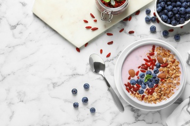 Photo of Flat lay composition of smoothie bowl with goji berries on marble table. Space for text