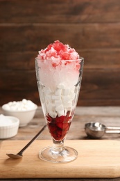 Photo of Glass of snow ice cream with raspberry and  marshmallow on table against wooden background