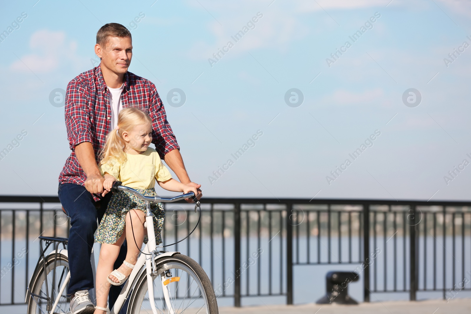 Photo of Father and daughter riding bicycle outdoors on sunny day